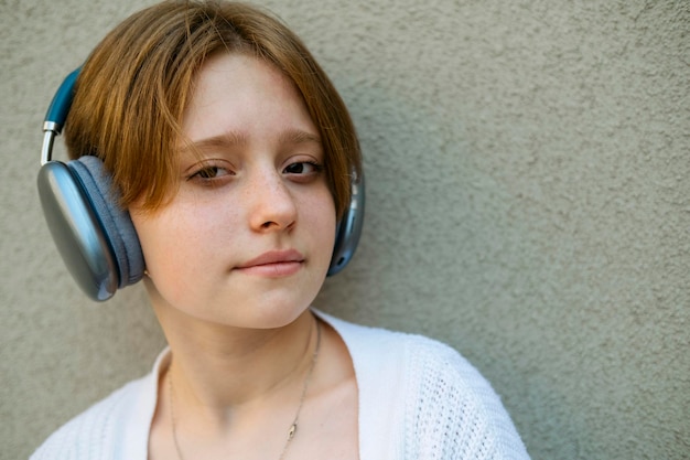 写真 灰色の壁にヘッドフォンをかけた十代の女の子の肖像画