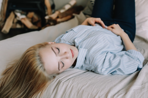 写真 スカンジナビアのインテリアおはようライフスタイルで自宅で朝のベッドで若い美しいブロンドの女の子の肖像画