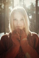 portrait of a young beautiful blonde woman in sweater posing in winter park. sunny day in forrest.