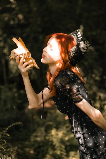 Фото Портрет молодой красивой девушки с рыжими волосами на природе с птичьими крыльями на голове