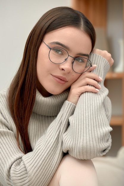 Фото Портрет молодой спокойной женщины в очках, смотрящей сквозь очки на камеру, снимок молодой деловой женщины в очках, стильные очки, модный аксессуар