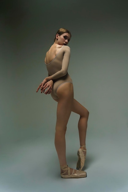 Фото Портрет молодой балерины, стоящей в закрытом положении с перекрестными руками за спиной