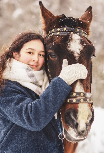 自然の中で冬の少女と馬の肖像画。閉じる。垂直