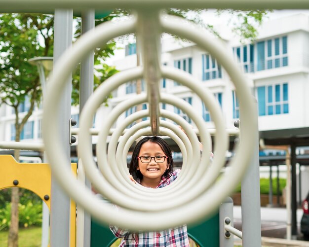 写真 庭の遊び場で遊んでいる眼鏡をかぶった若い女の子の肖像画