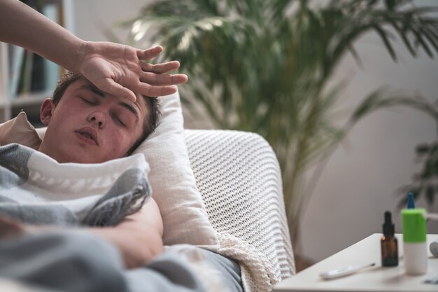 写真 ソファーで横になっていると彼の頭に手を置く若い病気の男の肖像画。