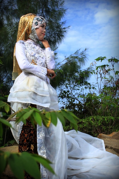 Фото Портрет молодой женщины, стоящей на растении в традиционном свадебном платье из индонезии