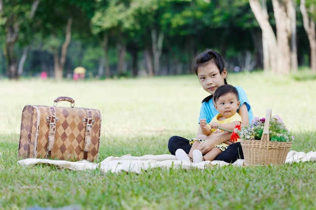 写真 愛らしい兄と妹の肖像画は笑顔と公園に座って抱き締めます。