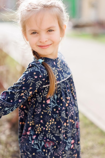 Фото Портрет очаровательной улыбающейся маленькой девочки в платье на открытом воздухе в летний день, фото высокого качества