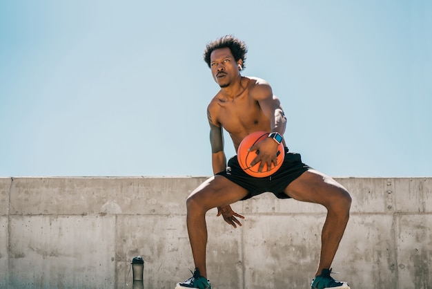 Фото Портрет афро-спортсмена, играющего и тренирующегося с баскетбольным мячом на открытом воздухе. спорт и здоровый образ жизни.