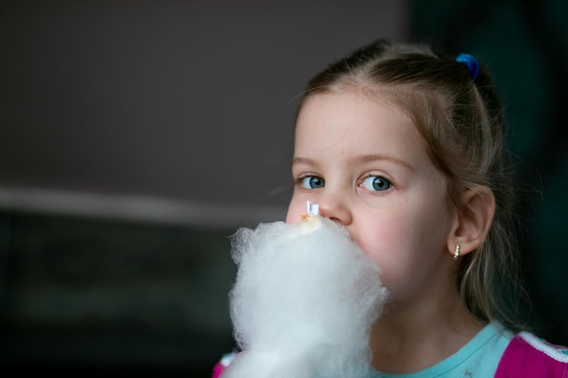 写真 おいしい白い綿菓子キャンディフロを食べる金髪の驚くべき少女の肖像画