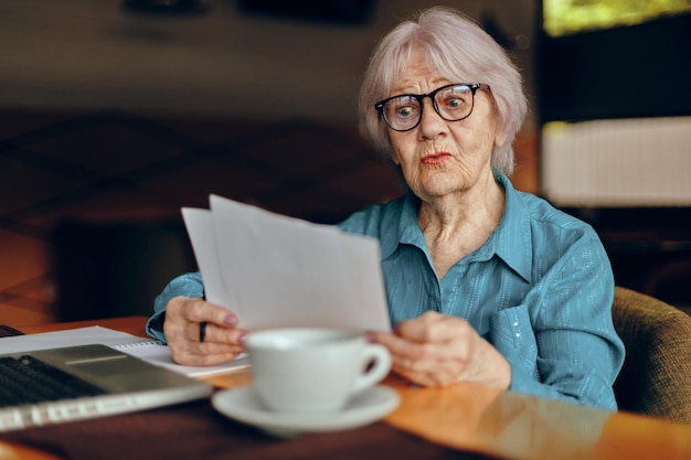 写真 一杯のコーヒーとラップトップを持ってカフェに座っている年配の女性の肖像画フリーランサーは変更されずに動作します