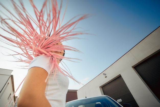 写真 空と車の背景にピンクのピグテールを持つ独立した女の子のポートレート、現代社会のコンセプト