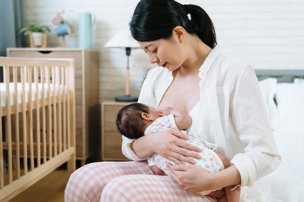 사진 그녀의 아기를 먹이는 아시아 밀레니엄 어머니의 초상화. 팔에 아이를 바라보는 순수한 기쁨을 경험하는 대만의 새 엄마. 모유 수유 촉진 개념