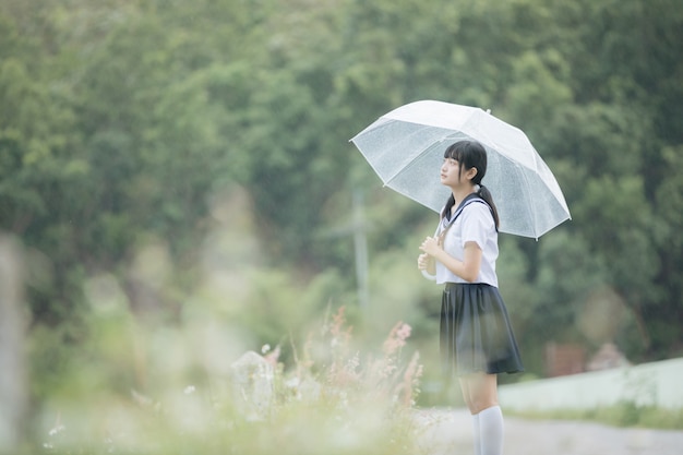 사진 비가에 자연 산책로에서 우산을 걷고 아시아 여고생의 초상화