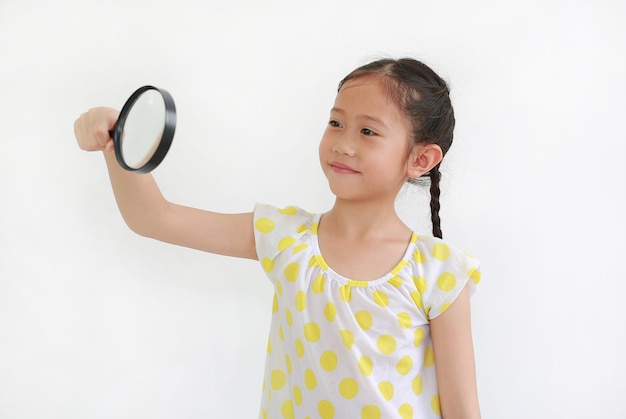 흰색 배경 위에 돋보기를 통해 찾고 아시아 어린 소녀 아이의 초상화.