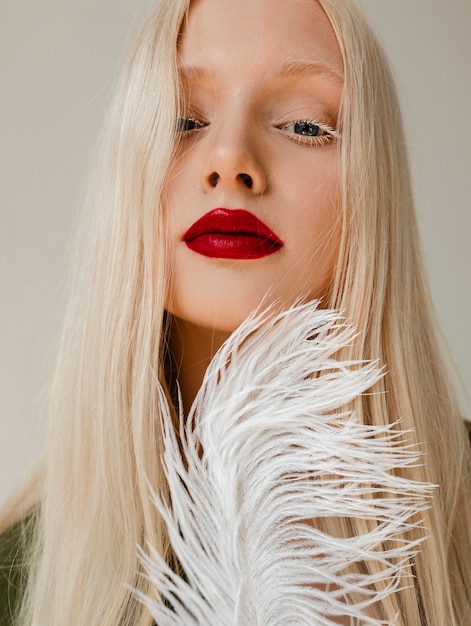 Фото Портрет красивой женщины-альбиноса с белым пером