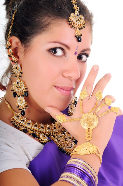 Портрет красивой девушки брюнетки с длинными волосами в традиционной голубой индийской одежде. массивные украшения на лице и рядом. изолированные на белом фоне