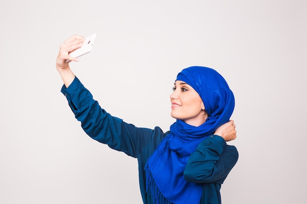 写真 ヒジャーブを着た美しいイスラム教徒の若い女性のポートレートは、携帯電話を使って自撮りをしている。