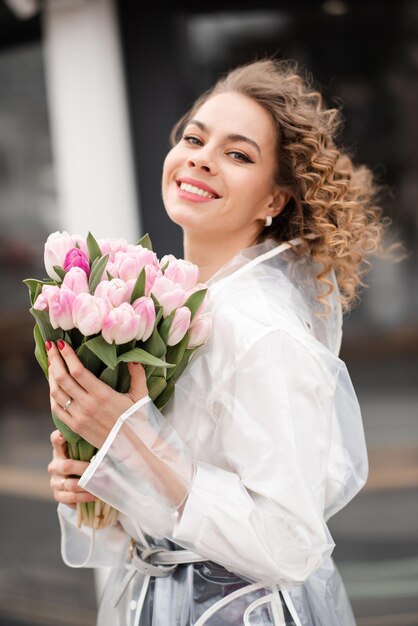 Фото Портрет красивой улыбающейся женщины с букетом тюльпанов на улице, смотрящей в камеру