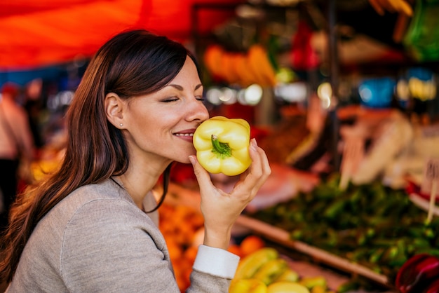 Фото Портрет паприки красивой женщины пахнуть на рынке. запах свежих овощей удивителен