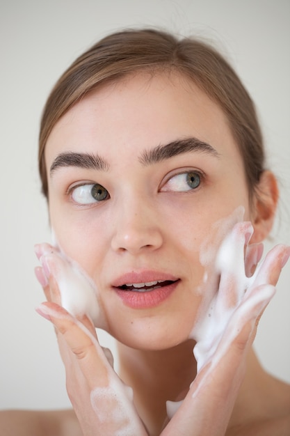 写真 フォームクレンザーで顔を洗う透明な肌を持つ美しい女性の肖像画