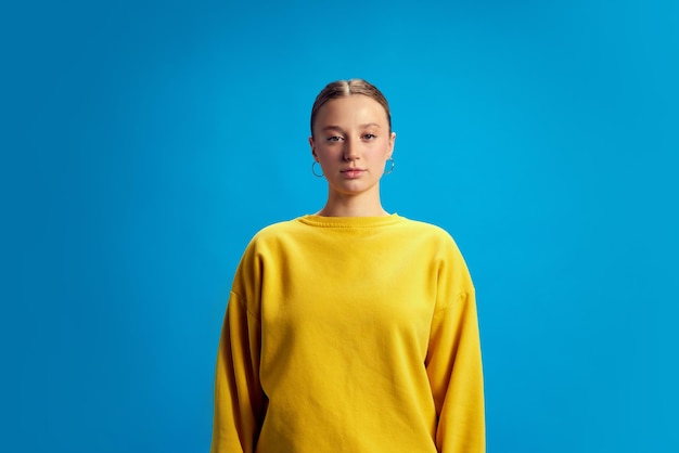 写真 黄色いスウェットシャツを着て立っている美しい若い女の子の肖像画