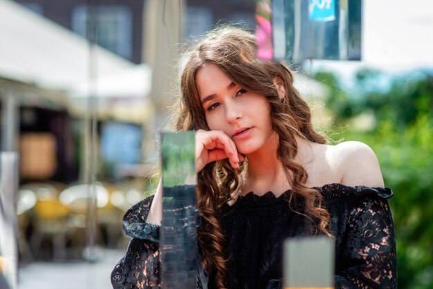 Фото Портрет красивой молодой женщины, сидящей в кафе на тротуаре