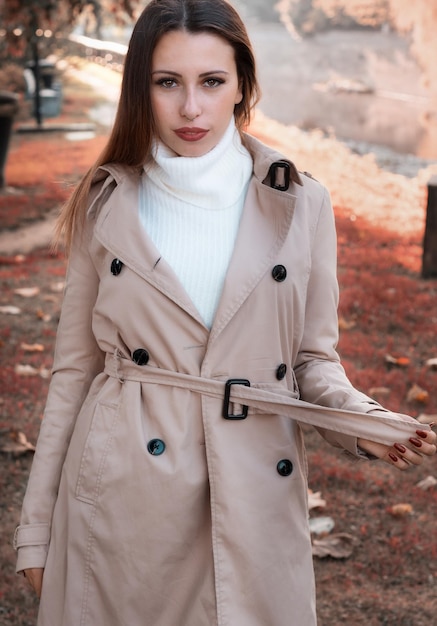 写真 外に立っている長いコートを着た美しい若い女性の肖像画