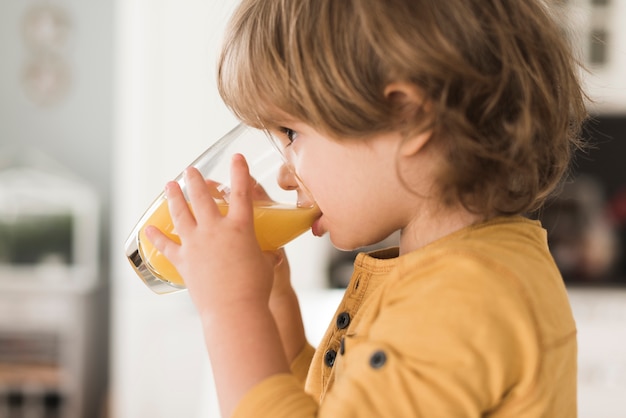 写真 オレンジジュースのガラスを飲む少年の肖像画