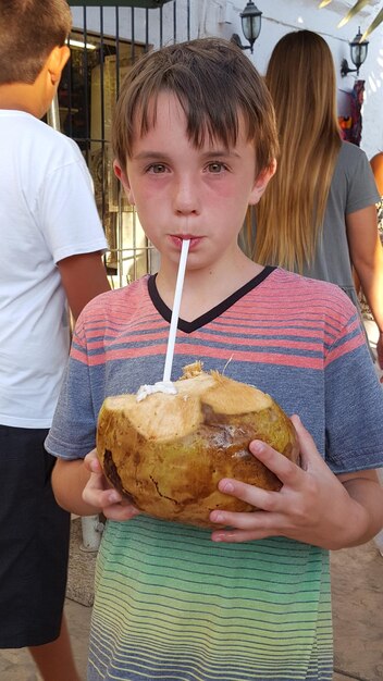 写真 屋外でココナッツを食べている男の子の肖像画