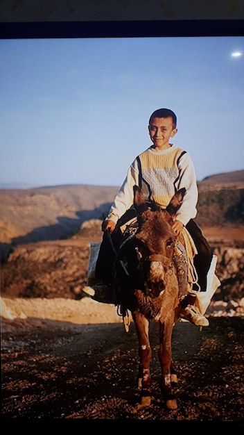 Фото Портрет мальчика, сидящего на ослике