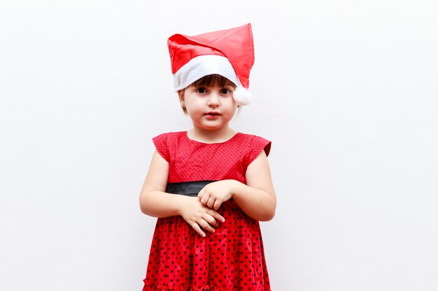 Фото Портрет кавказской малышки в новогодней шапке, на белом фоне