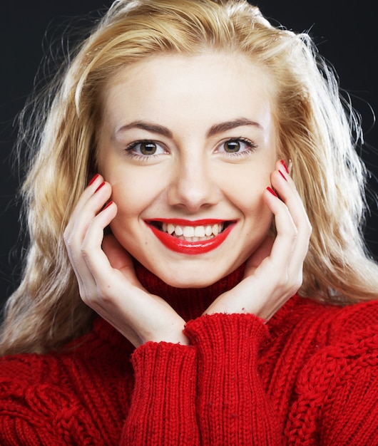 Фото Портрет очаровательной улыбающейся блондинки в красном свитере