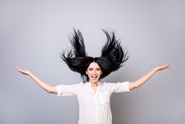 写真 飛んでいる髪と白いシャツの魅力的な笑顔の女性の肖像画