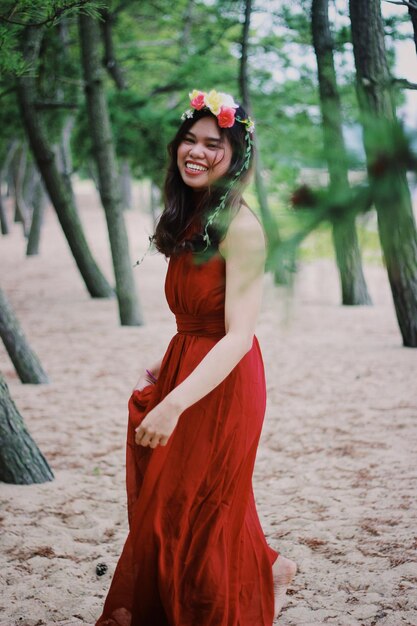 Фото Портрет веселой молодой женщины в красном платье, стоящей на пляже