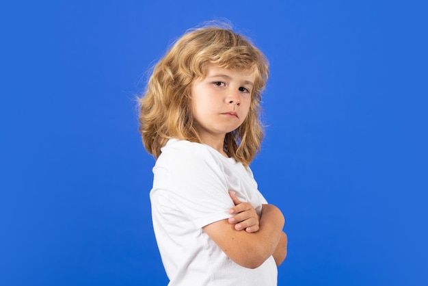 Фото Портрет ребенка со скрещенными руками на синем изолированном фоне студии злой ребенок расстроенный мальчик с безумным выражением лица