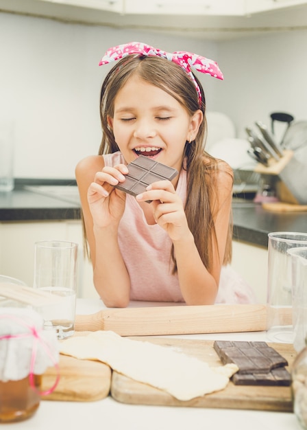 キッチンでダークチョコレートバーを噛んでかわいい女の子の肖像画