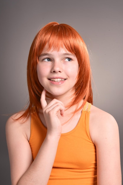 사진 스튜디오에서 포즈를 취하는 빨간 머리를 가진 귀여운 소녀의 초상화