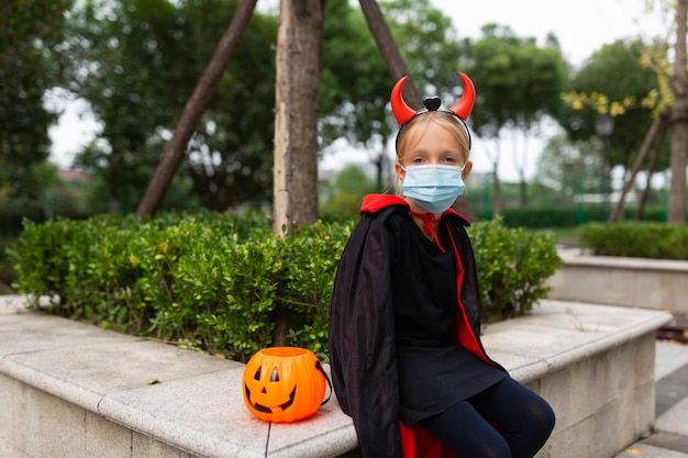 写真 公園で悪の衣装を着たかわいい少女の肖像画