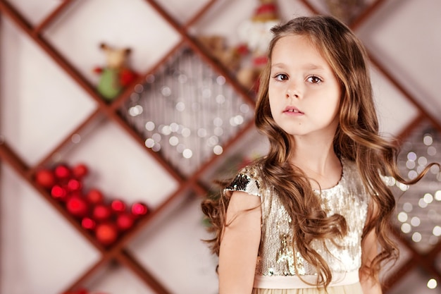 写真 クリスマスライトの背景にドレスでかわいい長髪の少女の肖像画