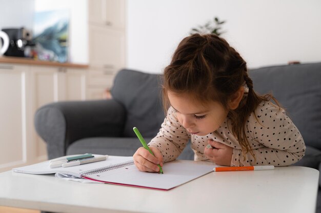 写真 家で筆で絵を描いている可愛い幼稚園児の女の子の肖像画