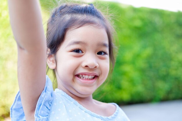 写真 屋外の植物に立っている可愛い笑顔の女の子の肖像画