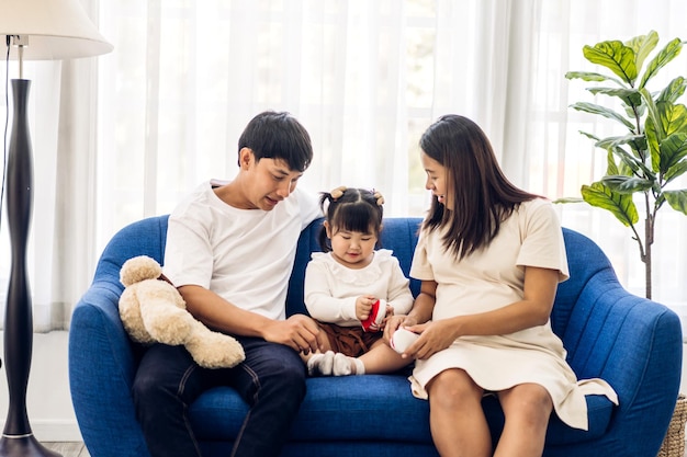 幸せな愛を楽しむの肖像アジアの家族の父と母は、抱擁かわいい小さなアジアの女の子の子供を笑顔で遊んで、家で楽しい時間を過ごしています