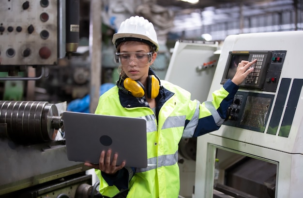 写真 工場の機械環境に対してラップトップで立っている女性エンジニアの肖像画