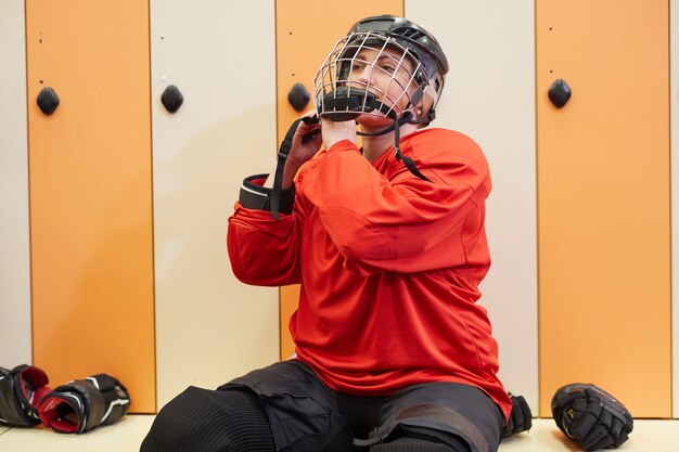 写真 ロッカールームでヘルメットをかぶっている女性のホッケー選手の肖像画