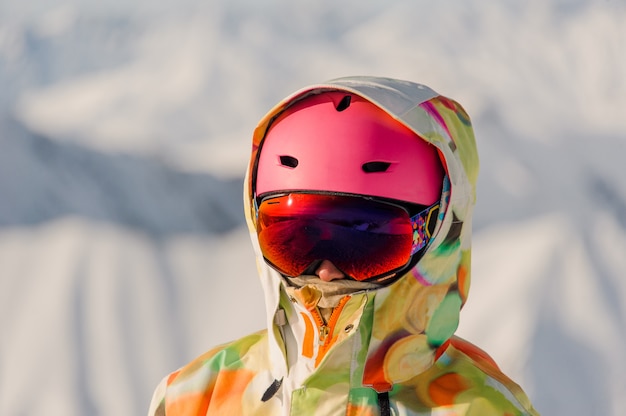 写真 ピンクのスポーツヘルメットと明るくカラフルなスポーツウェアの女性スノーボーダーの肖像画