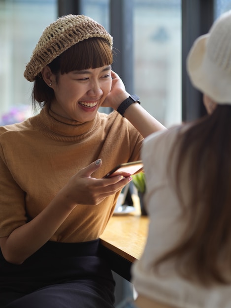 사진 스마트 폰을 사용하고 카페에 앉아있는 동안 친구와 이야기하는 여성 십대의 초상화