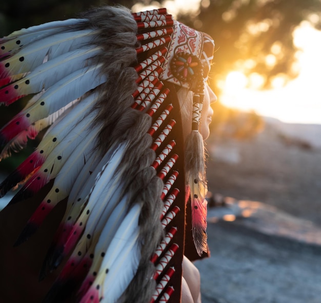 Фото Портрет девушки с руками в индейских головных уборах в природе в свете заката