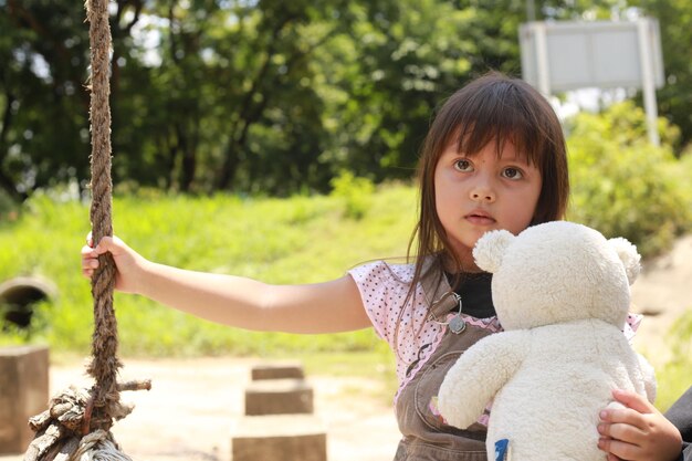 写真 木の向こうに玩具を持った女の子の肖像画