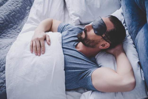 写真 ベッドに横たわって眠っているマスクのハンサムな男の肖像画